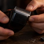 Manos revisando de cerca los dientes de la cuchilla de un cortapelos